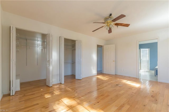 unfurnished bedroom with multiple closets, ceiling fan, connected bathroom, and light hardwood / wood-style floors