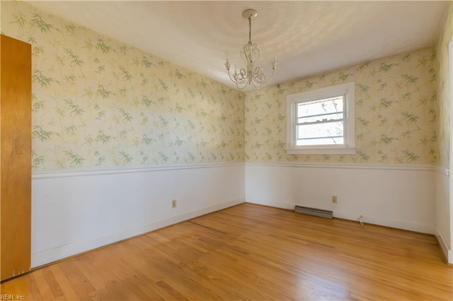 unfurnished room featuring a notable chandelier and wood-type flooring