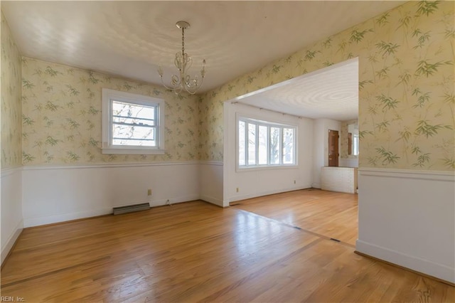 spare room with hardwood / wood-style floors and a notable chandelier