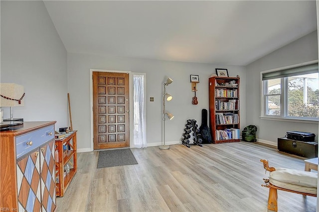 entryway with lofted ceiling, light wood-style flooring, and baseboards