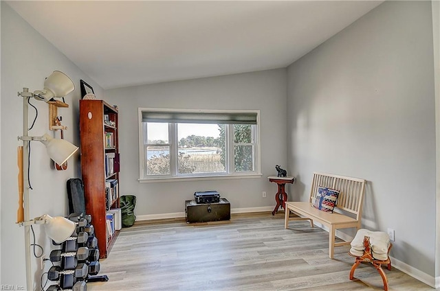 living area featuring lofted ceiling, light wood-style floors, and baseboards