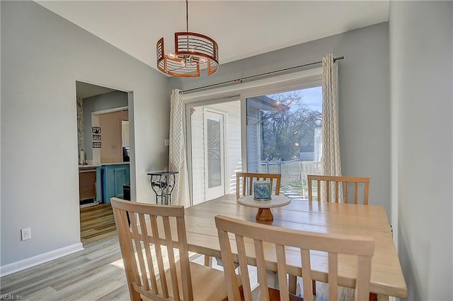 dining room with light wood-style floors, lofted ceiling, and baseboards