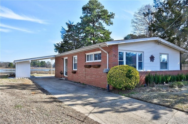 view of property exterior with a carport, driveway, and brick siding