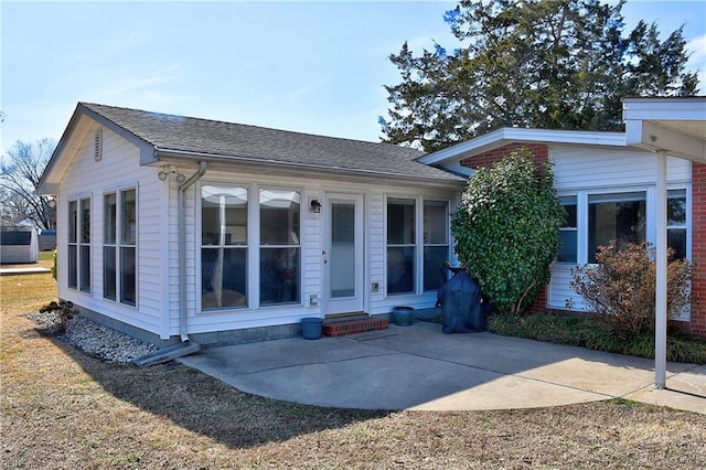 rear view of house featuring a patio area and roof with shingles