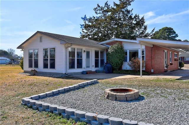 exterior space featuring a patio, a fire pit, a carport, and brick siding