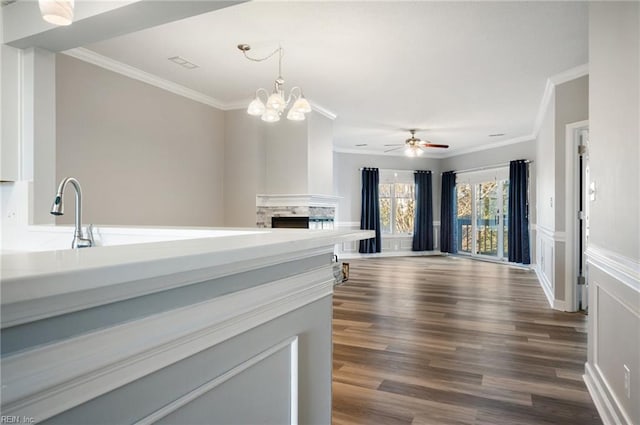 kitchen featuring sink, hanging light fixtures, dark hardwood / wood-style floors, ornamental molding, and ceiling fan with notable chandelier