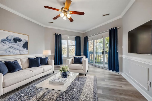 living room with light hardwood / wood-style flooring, ornamental molding, and ceiling fan