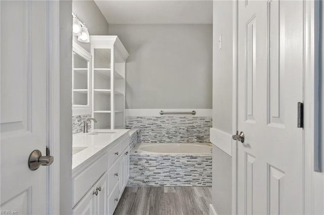 bathroom with vanity, wood-type flooring, and tiled bath