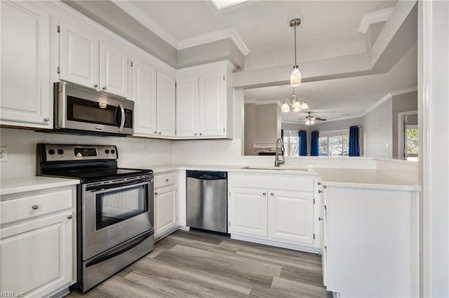 kitchen with sink, hanging light fixtures, stainless steel appliances, ornamental molding, and white cabinets