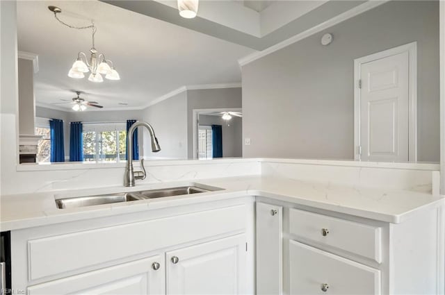 kitchen with pendant lighting, sink, white cabinets, ornamental molding, and ceiling fan