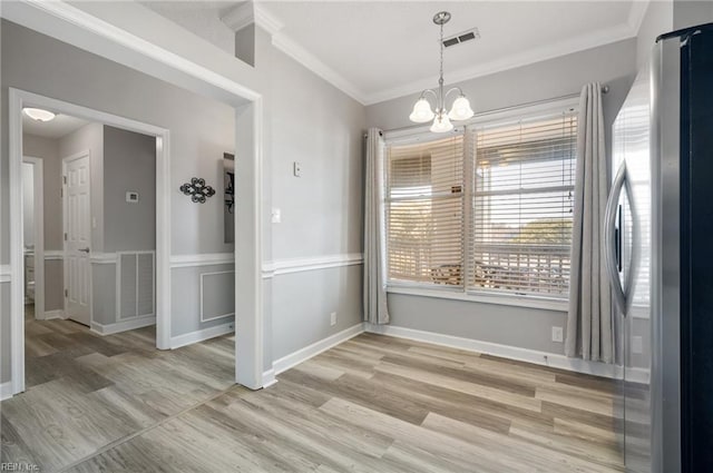 unfurnished dining area featuring crown molding, a chandelier, and light hardwood / wood-style flooring