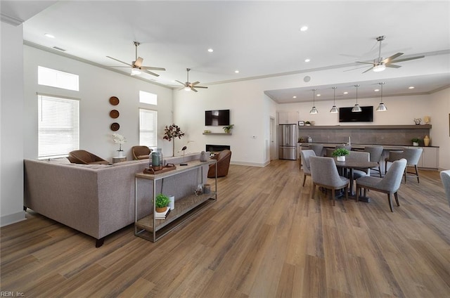 living room with hardwood / wood-style flooring, ornamental molding, and ceiling fan