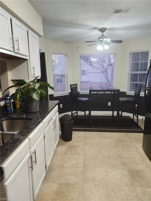 kitchen featuring dark stone counters, white cabinets, and light tile patterned flooring