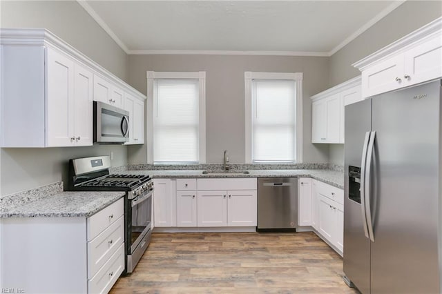 kitchen with sink, crown molding, white cabinetry, stainless steel appliances, and light stone countertops