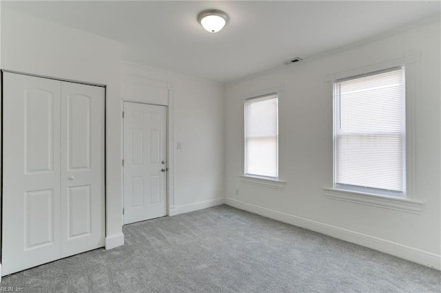 unfurnished bedroom with light colored carpet and a closet