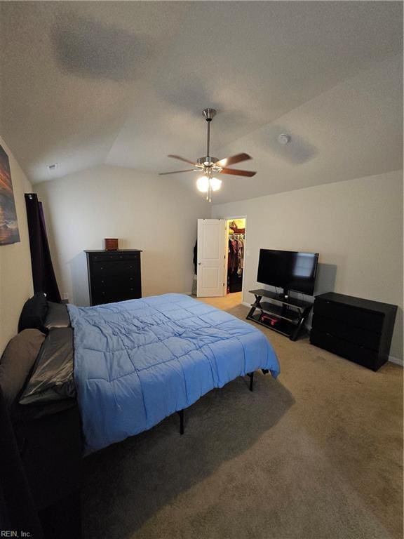 bedroom with lofted ceiling, carpet flooring, a spacious closet, ceiling fan, and a textured ceiling