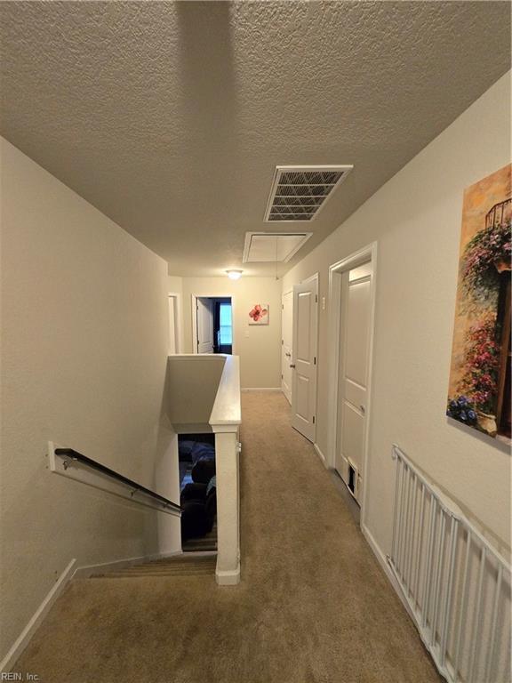 corridor with carpet flooring, radiator, and a textured ceiling