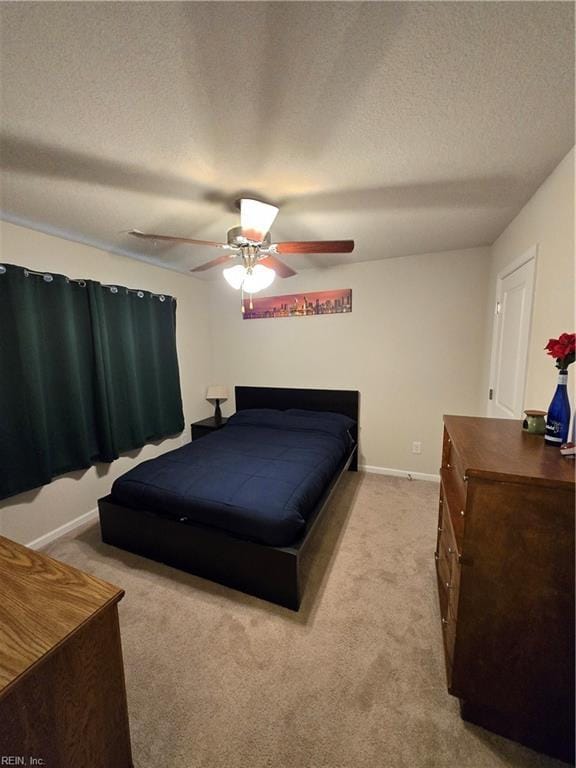 carpeted bedroom featuring ceiling fan and a textured ceiling