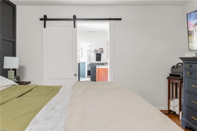 bedroom with a barn door and dark hardwood / wood-style flooring