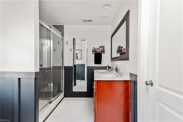 bathroom with an enclosed shower, vanity, and a textured ceiling