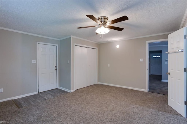 unfurnished bedroom with crown molding, a closet, dark carpet, and a textured ceiling