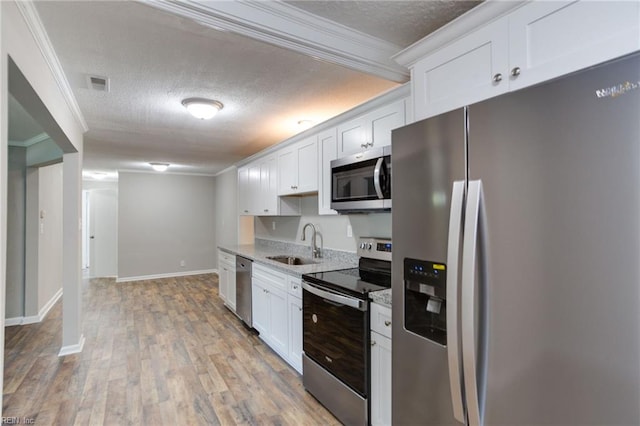 kitchen with sink, appliances with stainless steel finishes, white cabinetry, ornamental molding, and a textured ceiling