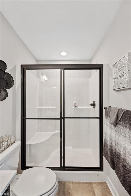 bathroom featuring a shower with door and toilet