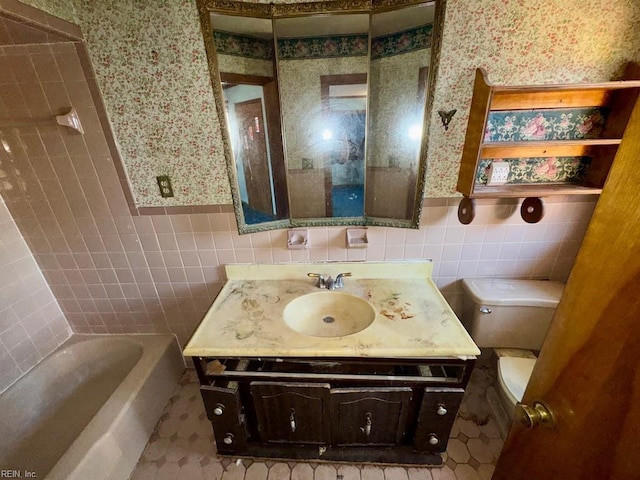 bathroom with vanity, tile walls, a bathtub, and toilet