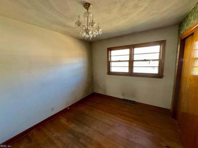 unfurnished room featuring dark hardwood / wood-style flooring and a chandelier