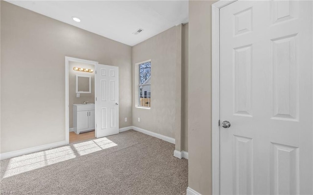 unfurnished bedroom featuring ensuite bathroom and light carpet