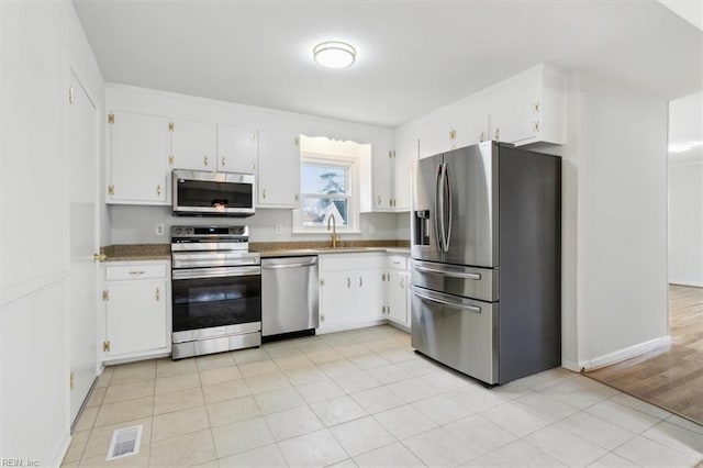 kitchen with white cabinetry, stainless steel appliances, sink, and light tile patterned floors