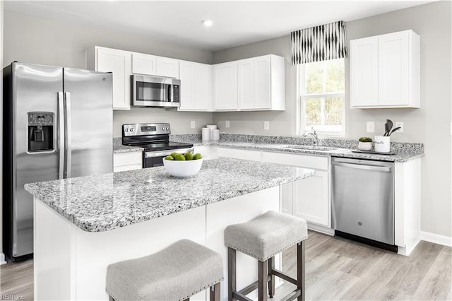 kitchen featuring sink, stainless steel appliances, a center island, and white cabinets