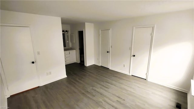 unfurnished bedroom featuring two closets and wood-type flooring