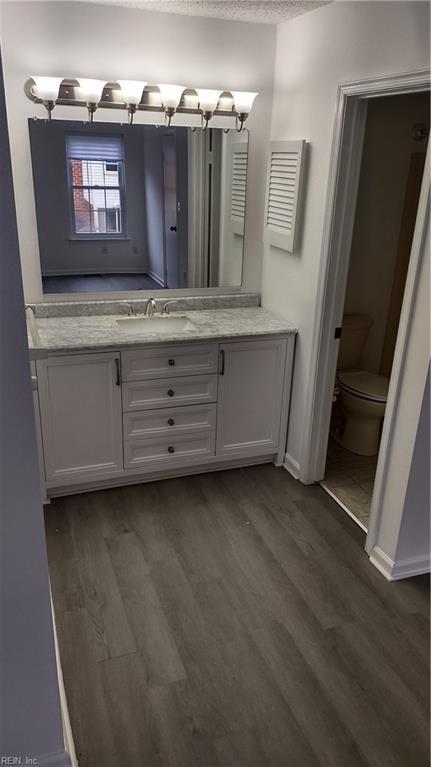 bathroom featuring hardwood / wood-style flooring, vanity, toilet, and a textured ceiling