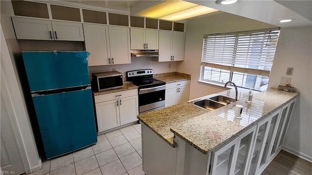 kitchen featuring sink, white cabinets, kitchen peninsula, stainless steel appliances, and light stone countertops