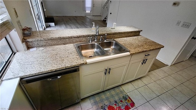 kitchen featuring light stone counters, sink, stainless steel dishwasher, and light tile patterned flooring