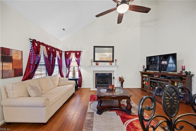 living room with hardwood / wood-style flooring, ceiling fan, and high vaulted ceiling