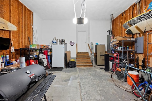 garage featuring water heater, electric panel, white refrigerator, and a workshop area