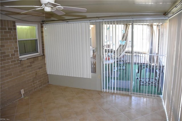 spare room with ceiling fan, brick wall, and light tile patterned floors