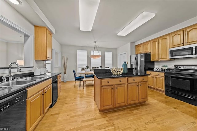 kitchen featuring sink, hanging light fixtures, a center island, light hardwood / wood-style floors, and black appliances