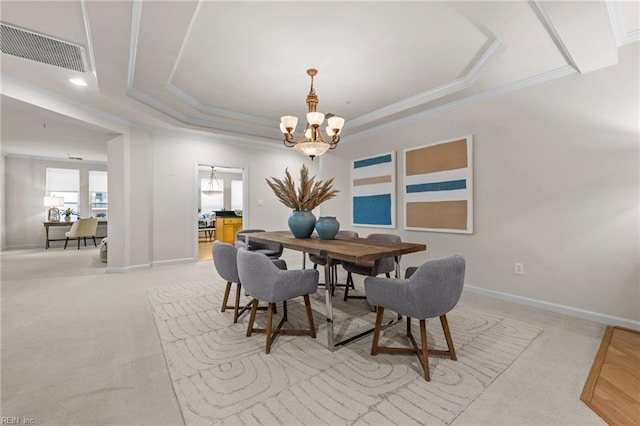 dining room featuring a raised ceiling, ornamental molding, light carpet, and a notable chandelier