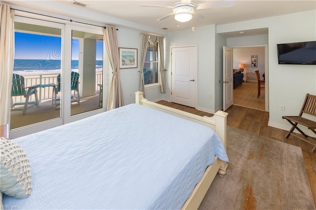 bedroom featuring a water view, ceiling fan, wood-type flooring, and access to exterior