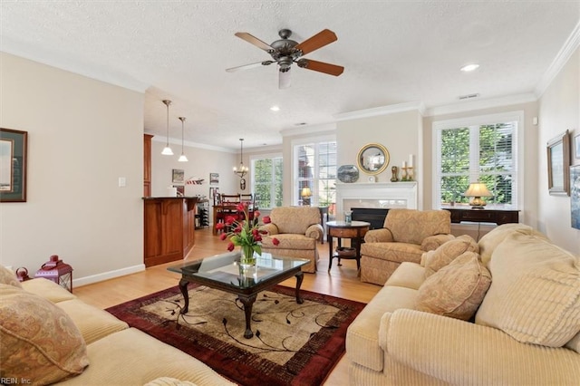 living room with ceiling fan, ornamental molding, a wealth of natural light, and light hardwood / wood-style flooring