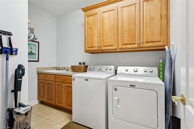 washroom with washing machine and clothes dryer, sink, cabinets, and light tile patterned floors