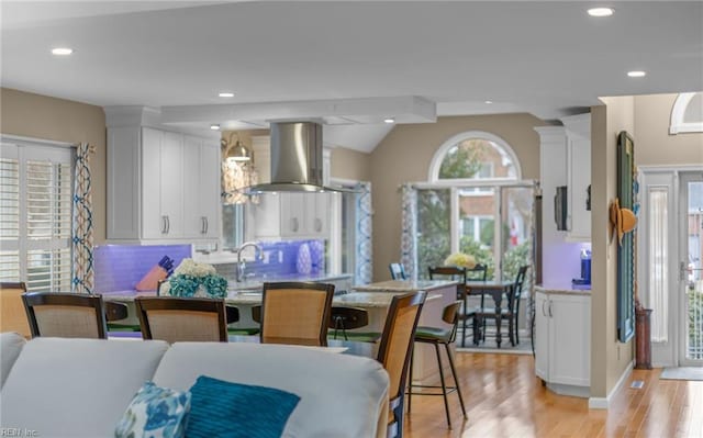 dining space featuring sink, light hardwood / wood-style flooring, and ornate columns