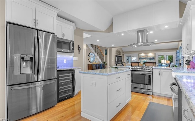 kitchen with white cabinetry, stainless steel appliances, wine cooler, light stone counters, and island exhaust hood