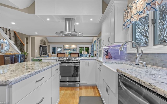 kitchen with stainless steel appliances, island exhaust hood, white cabinets, and light wood-type flooring