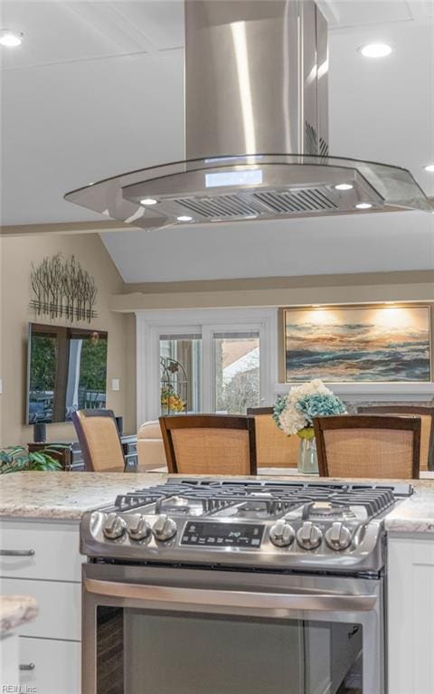 kitchen featuring white cabinetry, light stone counters, island range hood, and gas stove