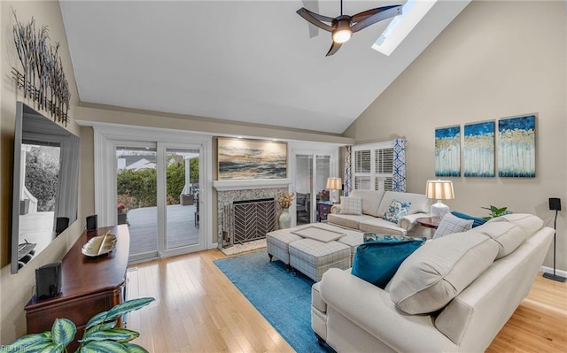 living room with high vaulted ceiling, hardwood / wood-style floors, ceiling fan, and a skylight