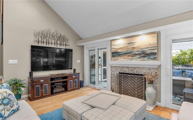 living room with wood-type flooring, a premium fireplace, and vaulted ceiling